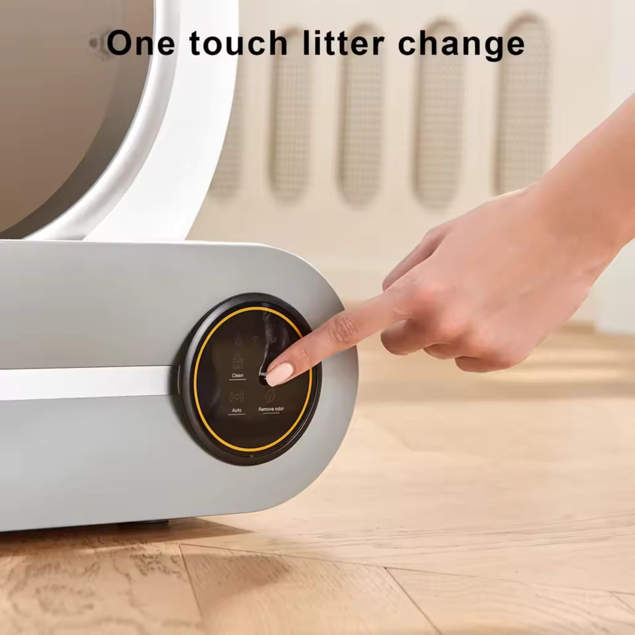 A hand presses a button on the Strike Algo Automatic Cat Cleaning Litter Box. One-touch litter change is displayed above the sleek grey unit, which sits on a wooden floor.